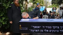 דני אלגרט ליד ארונו של אחיו איציק אלגרט ז"ל (צילום: בן כהן/דוברות ניר עוז)