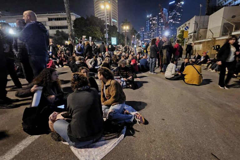 מפגינים למען שחרור החטופים יושבים על שדרות שאול המלך בתל אביב סמוך לשער בסיס הקריה (צילום: דורון הבסי)