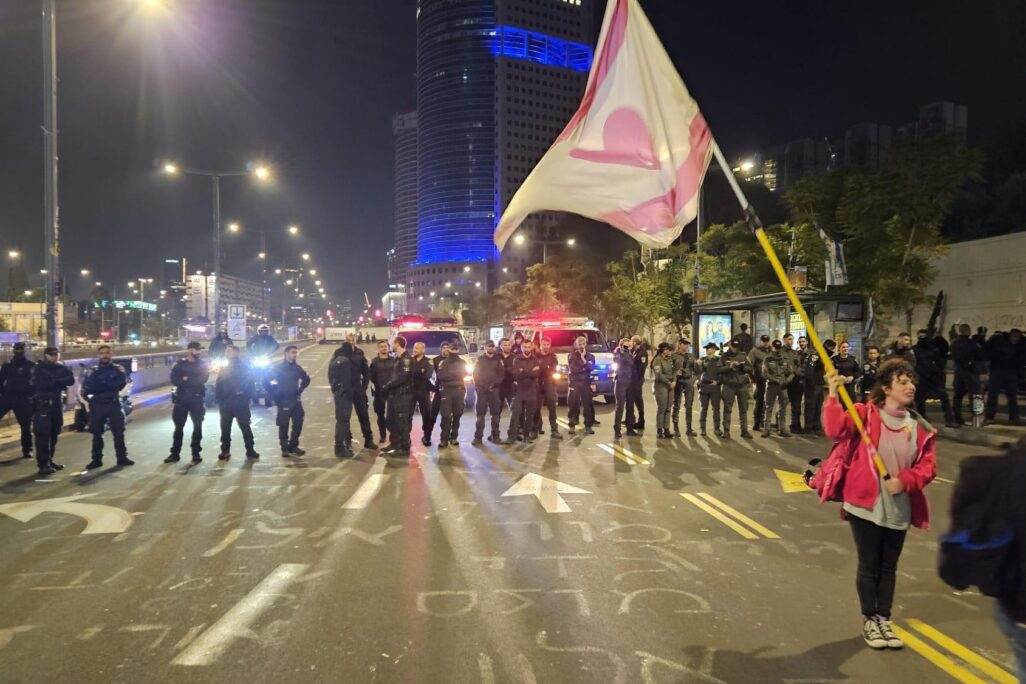 מפגינה במחאה לשחרור חטופים שמאחוריה שורת שוטרים בדרך בגין בתל אביב (צילום: דורון הבסי)