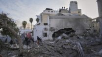 פלסטינים ליד הריסות בבית החולים 'אל אהלי' שצה"ל הפציץ (צילום: AP Photo/Jehad Alshraf)