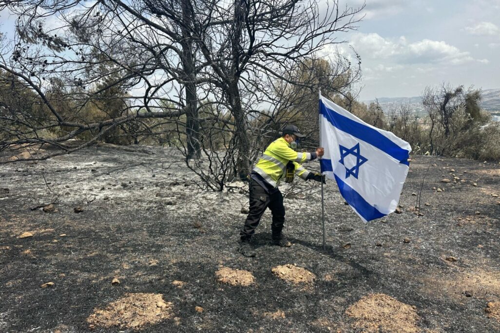 נהג כבאית בקק״ל רן נעים, מניף את דגל ישראל בלב השריפה בפארק קנדה (צילום: קק"ל) נהג כבאית בקק״ל רן נעים, מניף את דגל ישראל בלב השריפה בפארק קנדה (צילום: קק"ל)