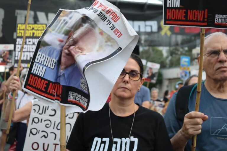 מפגינה עם שלט שהושחת (צילום: קרולין דרוויל)