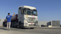 עובד ב'תוכנית המזון העולמית של האו"ם מברך נהג משאית שהגיע למעבר רפיח עם משאיות סיוע הומניטרי לרצועת עזה, 27 ביולי 2025 (צילום: AP Photo/Mohamed Arafat)
