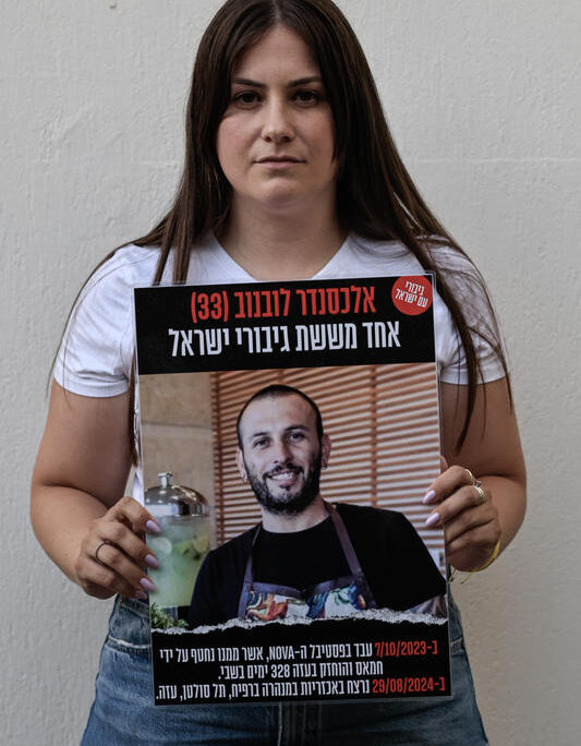 מיכל לובנוב, אלמנתו של אלכסנדר, נושאת שלט לזכרו במעמד השנה להירצחו (צילום: צפריר אביוב/פלאש90)