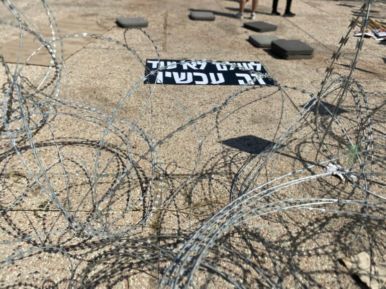 סטיקר "לעולם לא עוד זה עכשיו" במיצג גדרות התיל בכיכר החטופים (צילום: יהל פרג')