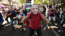 מפגינים נגד הצנע בצרפת עם מסכה בדמות איל ההון הצרפתי ברנאר ארנו והכיתוב הפרודי 'כושר פיסקלי' (צילום: dpa via Reuters Connect)