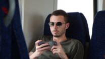 גבר מסתכל בטלפון הסלולרי במהלך נסיעה ברכבת ישראל. המצולם לא קשור לכתבה (אילוסטרציה: Avakov, shutterstock)