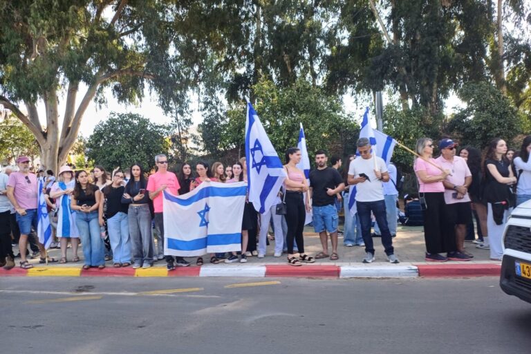 Residents stand with flags at the funeral procession of the late Inbar Hayman (Photo: Amitai Perez)