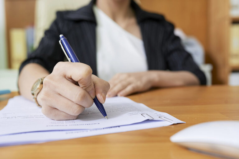 Hands of social worker writing personal data of patient in document