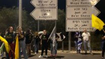 תושבי המועצה האזורית אשכול בצומת גמה מחכים למעבר השיירה המעבירה את ארונות החטופים החללים למכון לרפואה משפטית (צילום: יהל פרג')