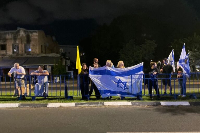 אזרחים עם דגלי ישראל ממתינים להבאת החטופים החללים למרכז הלאומי לרפואה משפטית באבו כביר (צילום: יהל פרג')