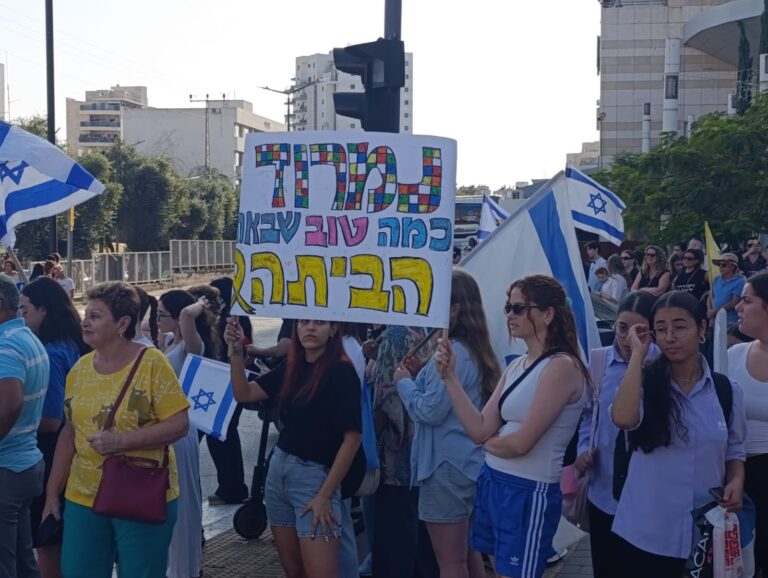אישה נושאת שלט "נמרוד, כמה טוב שבאת הביתה" בעיר רחובות (צילום: אסף צבי)