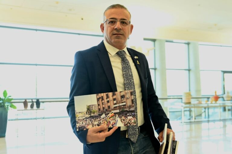 ההיסטוריון אמיר ח'ניפס עם תמונת כיכר העיר בסווידא, ובה מונף דגל ישראל (צילום: אור גואטה)