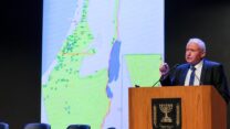 אבי דיכטר נואם בכנס הרפתנים בכנס לצד מפת רפתות החלב בישראל (צילום: יוסי אלוני)