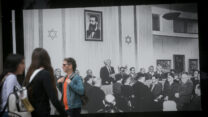 אנשים חולפים על פני תמונה של הכרזת העצמאות (צילום: מירים אלסטר / פלאש 90)