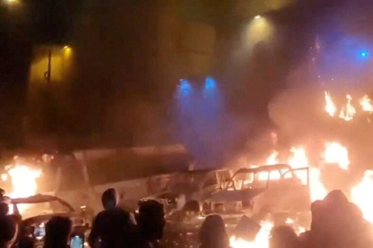 מפגינים בטהרן עומדים מול מכוניות שהוצתו בהפגנה (צילום: Social Media/via REUTERS)
