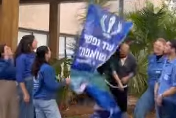 איתן הורן מוריד שלט שקרא לשחרורו, לצד מדריכים ורכזים שעבדו איתו בתנועת המחנות העולים (צילום: המחנות העולים)