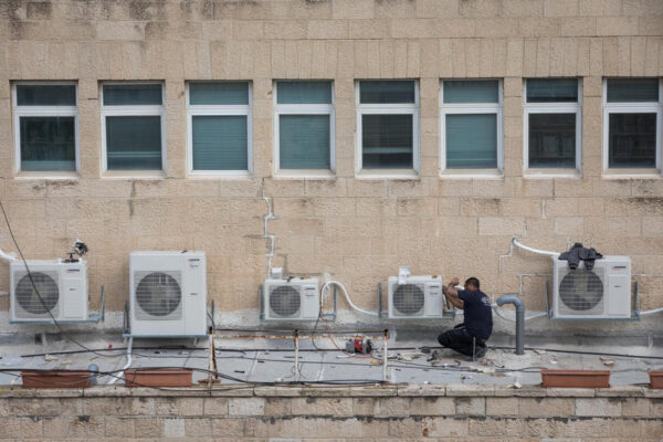 עובד מתקין מיזוג אוויר על גג בניין משרדים בירושלים. המצולם לא קשור לכתבה (צילום: נתי שוחט/פלאש90)