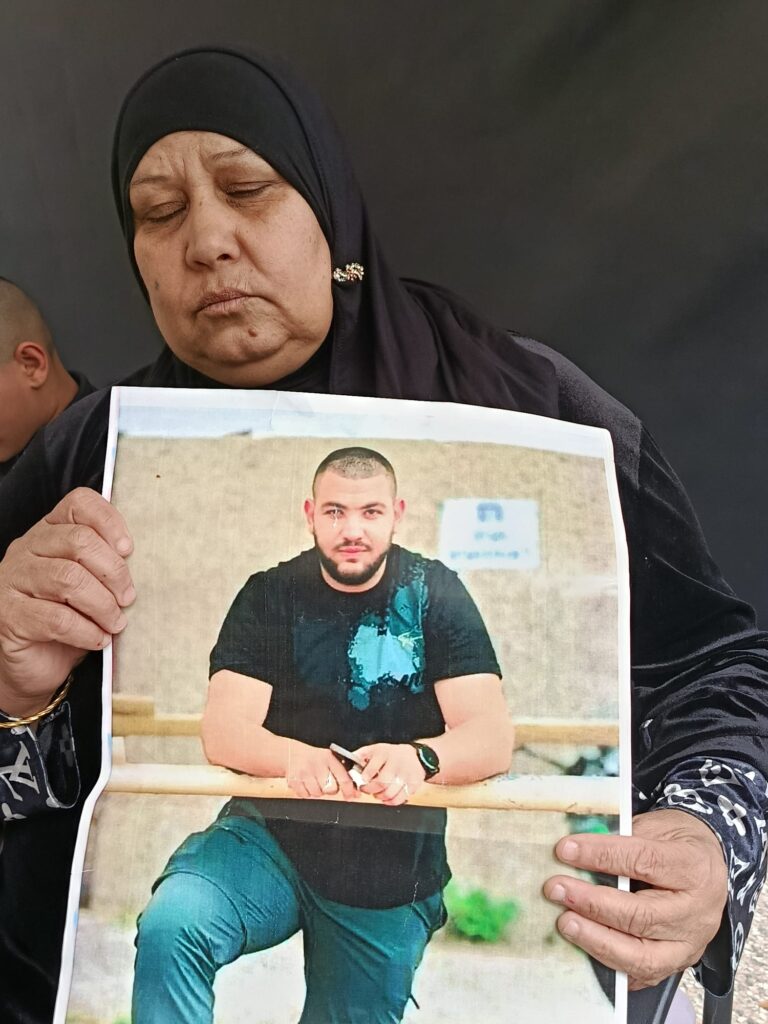 בושרא עמאש עם תמונת בנה עימאד (צילום: יניב שרון)