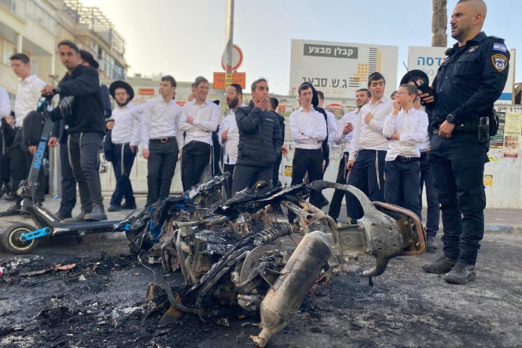 שוטר וקבוצת חרדים סמוך לאופנוע משטרתי שנשרף במהלך הפגנות חרדים בבני ברק (צילום: יהל פרג') שוטר וקבוצת חרדים סמוך לאופנוע משטרתי שנשרף במהלך הפגנות חרדים בבני ברק (צילום: יהל פרג')