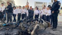 שוטר וקבוצת חרדים סמוך לאופנוע משטרתי שנשרף במהלך הפגנות חרדים בבני ברק (צילום: יהל פרג')