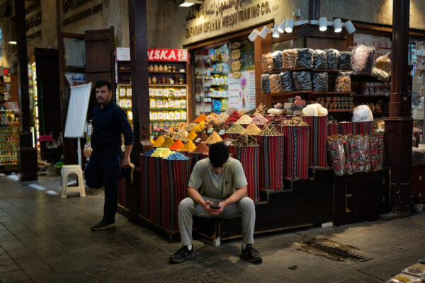 מוכר בחנות בדואבי מסתכל בטלפון (צילום: AP Photo/Altaf Qadri)