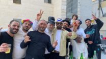 רב השכונה שנפגעה מטיל איראני בבית שמש, הרב יוסף עובדיה, עם תושבים החוגגים את פורים בזירת האסון (צילום: יהל פרג')