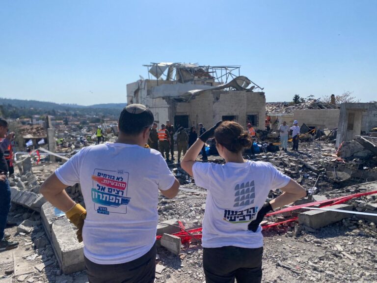 מתנדבים בזירת הפגיעה הישירה בבית שמש. "עושים הכול כדי להוציא כל פיסה מהבית" (צילום: יהל פרג')