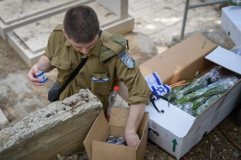 חייל מניח נרות זיכרון, דגלונים וזרים על קבריהם של חללי צה"ל בחלקה הצבאית (צילום: יונתן בלום)