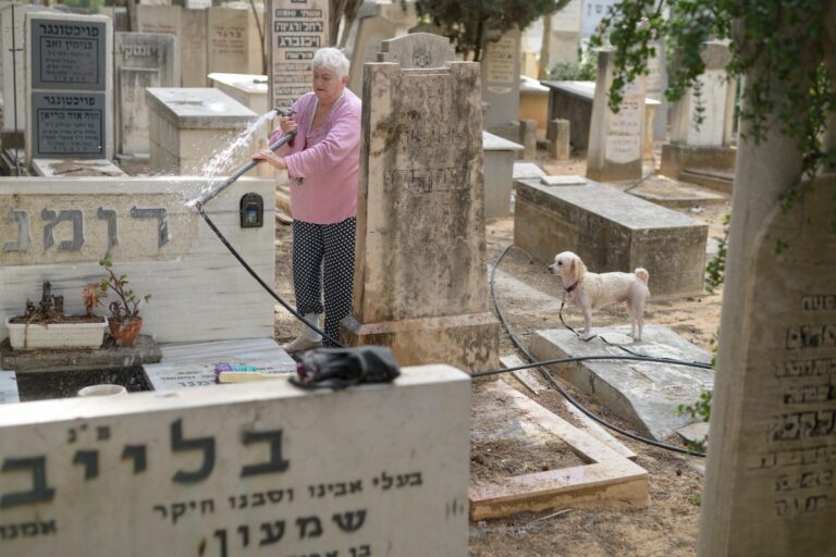 דליה שוטפת את המצבה של הוריה, עם הכלבה אנג'לינה. היא מגיעה לבית העלמין פעמיים בשנה, בפסח ובראש השנה. השנה, בגלל המלחמה עם איראן, הביקור של פסח נדחה(צילום: יונתן בלום)