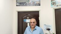 ווליד מולא בכניסה למשרדו, כשמעל לדלת תמונת פנורמה של מסע לזכרו של אביו, רשיד מולא ז"ל (צילום: יניב שרון)