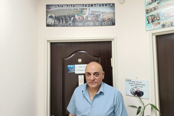 ווליד מולא בכניסה למשרדו, כשמעל לדלת תמונת פנורמה של מסע לזכרו של אביו, רשיד מולא ז"ל (צילום: יניב שרון)