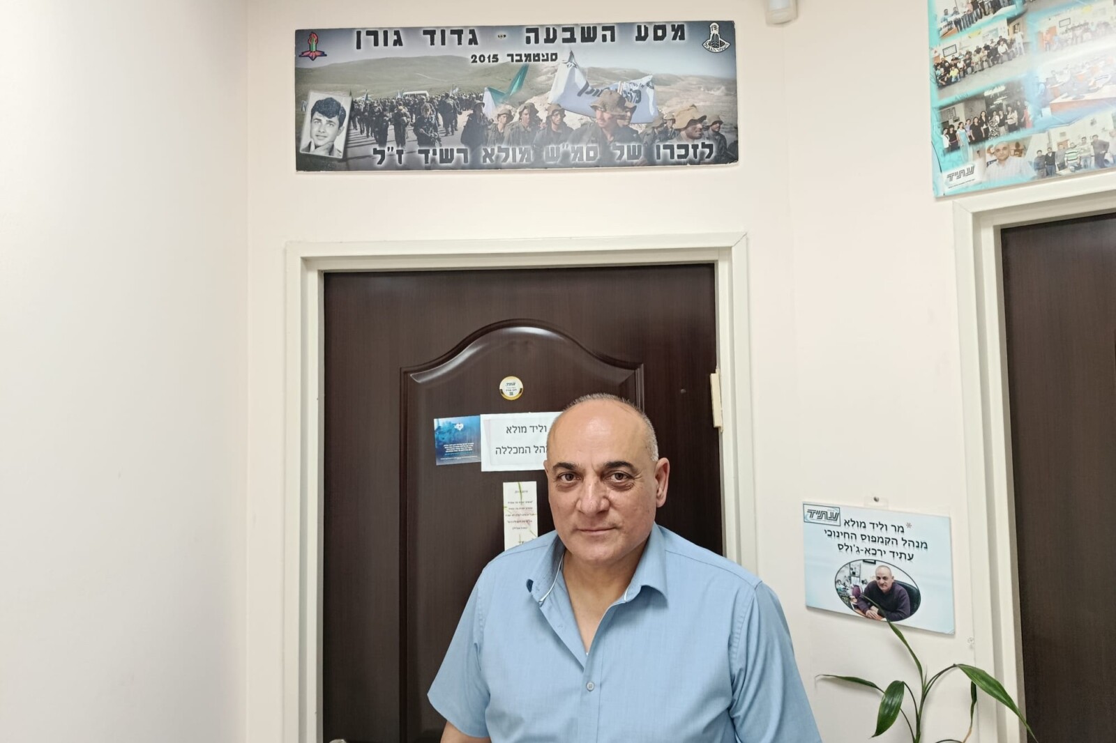 ווליד מולא בכניסה למשרדו, כשמעל לדלת תמונת פנורמה של מסע לזכרו של אביו, רשיד מולא ז"ל (צילום: יניב שרון)
