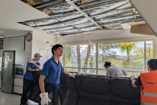 שחר פינאל (מימין), אסף שליט ובן ברנדס, מתנדבי שנת שירות בבני המושבים, מסייעים לארגן בית שנפגע מטיל במושב אשתאול. "מי שנפגע לו הבית לא צריך להתמודד עם זה לבד" (צילום: מיכל מרנץ)