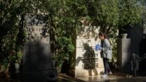 שרית טונדובסקי מניחה דגל ישראל ליד האנדרטה לקהילת ז'ולקיב בבית העלמין נחלת יצחק (צילום: יונתן בלום)