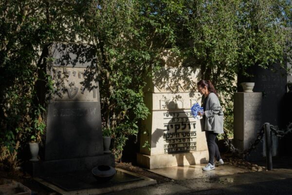 שרית טונדובסקי מניחה דגל ישראל ליד האנדרטה לקהילת ז'ולקיב בבית העלמין נחלת יצחק (צילום: יונתן בלום)