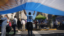 עובד מניף דגל ענק של ארגנטינה בהפגנת אחד במאי בבואנוס איירס  (צילום: AP Photo/Rodrigo Abd)