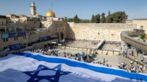 אנשים מחזיקים דגל ישראל ברחבת הכותל אחרי צעדת הדגלים בירושלים (צילום: פלאש 90)
