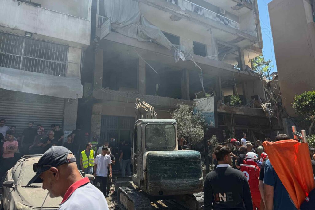 אנשים מתאספים בזירת התקיפה האווירית שפגעה בדירה בדאחיה, יום ראשון, 14 ביוני 2026. (צילום: AP/בילאל חוסיין)