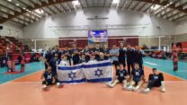 שחקני הנבחרת והמאמן נועם כץ מתעטפים בדגל ישראל וחוגגים ניצחון מוחץ בדרך לפודיום באליפות אירופה (צילום: איגוד הכדורעף)