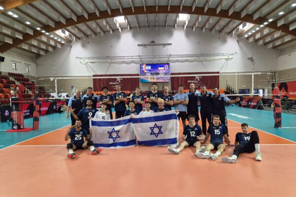 שחקני הנבחרת והמאמן נועם כץ מתעטפים בדגל ישראל וחוגגים ניצחון מוחץ בדרך לפודיום באליפות אירופה (צילום: איגוד הכדורעף)