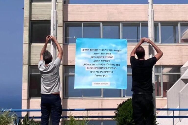 תליית כרזה עם קטע ממטרות החינוך הממלכתי במרכז החינוך לאו בק בחיפה, ספטמבר 2025 (צילום: איתמר כגן, משמר החינוך הממלכתי)