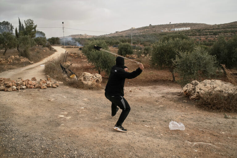 פורע רעול פנים מיידה אבנים באמצעות רוגטקה על המוסקים (צילום: AP Photo/Leo Correa)
