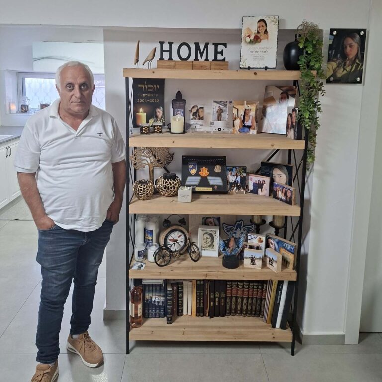 דרור אשרם ליד כוננית מזכרות מבתו שי. "אני מאז חי-מת, חצי עובד, וכל הזמן מנסה לפחות שיהיה משהו לזכרה" (צילום: אמיתי פרץ)