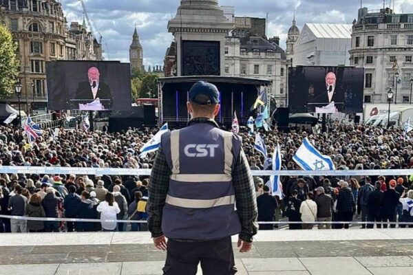 איש CST מאבטח עצרת של הקהילה היהודית בלונדון הצופה בדברי הרב הראשי של בריטניה אפרים מירוויס (צילום: CST)